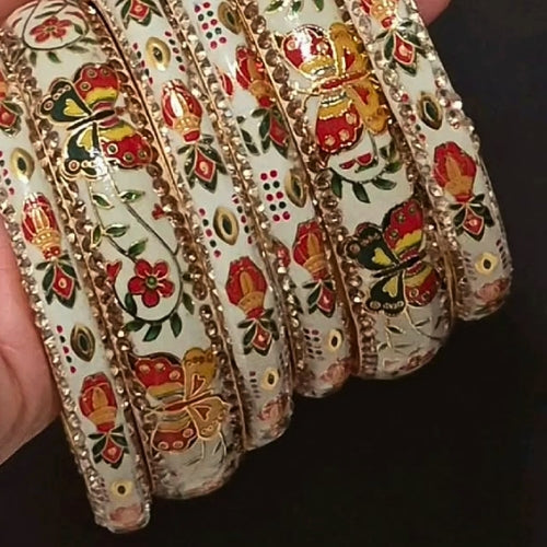 Decorative bangles with floral and butterfly patterns on a dark background